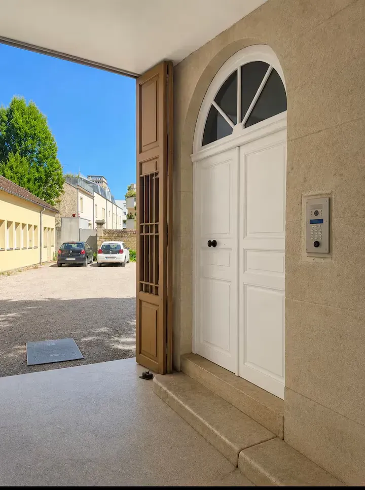 Entrée de l'immeuble de La Suite Devosge à Dijon avec porte d'accès et interphone