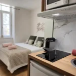 Studio ouvert de La Suite Devosge à Dijon avec espace nuit et coin cuisine équipé côte à côte