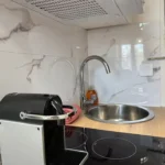 Détail du plan de travail cuisine de La Suite Devosge à Dijon : machine à café, plaque à induction et évier