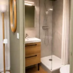 Salle de bain moderne de La Suite Devosge à Dijon avec douche à l'italienne, vasque en bois et miroir rond
