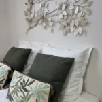 Chambre de La Suite Devosge à Dijon : tête de lit avec coussins verts et blancs et décoration murale en feuilles métalliques